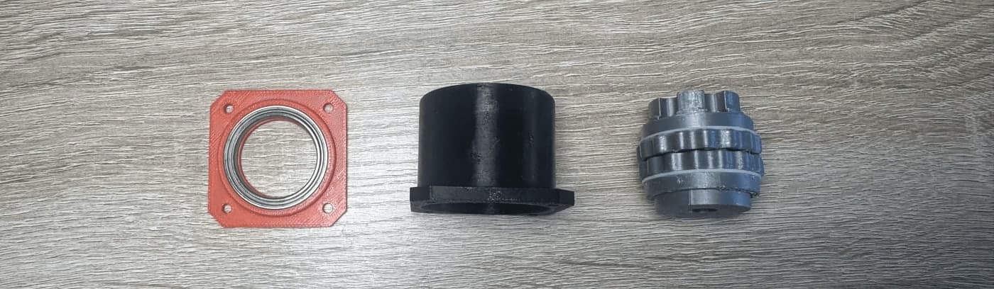 Three gearbox sub-assemblies: the orange closeout with a bearing seated in it, the black casing, and the eccentric shaft stacked with both cycloidal rings.