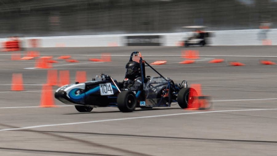 The car cornering through a cone course during a dynamic event, panned with motion blur.